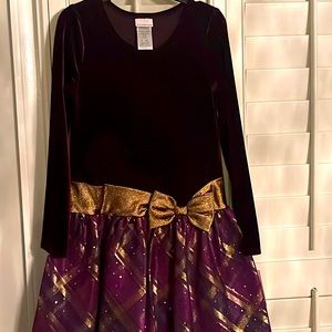 A formal dark purple dress with a gold ribbon and gold patterns on the bottom.